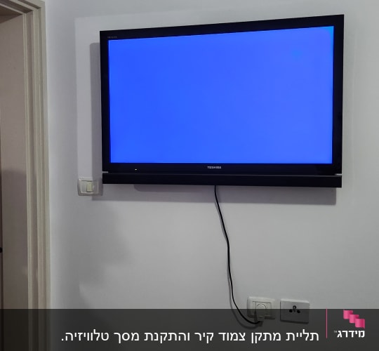 טלוויזיה תלויה על הקיר עם כבל חשמל